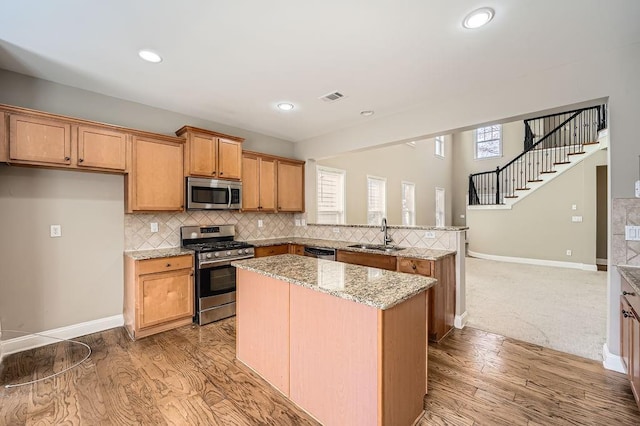 kitchen featuring visible vents, decorative backsplash, appliances with stainless steel finishes, light stone countertops, and a sink