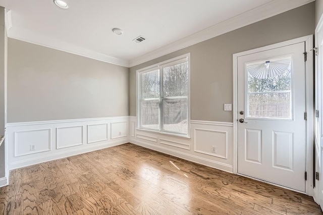 entryway featuring light wood-type flooring, visible vents, ornamental molding, and wainscoting