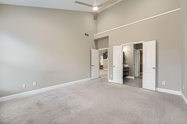 unfurnished bedroom featuring a high ceiling, baseboards, visible vents, and carpet flooring