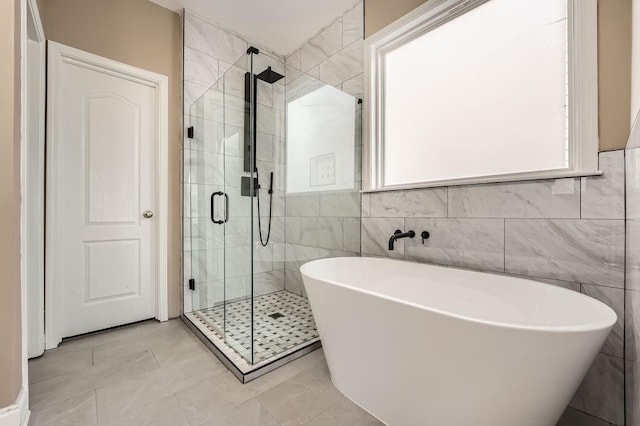 bathroom with plenty of natural light, a soaking tub, a shower stall, and tile walls