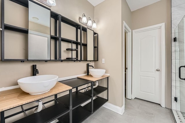 bathroom featuring tile patterned flooring, a shower stall, baseboards, and a sink