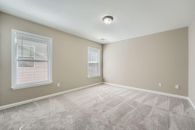 unfurnished room with visible vents, baseboards, and light colored carpet