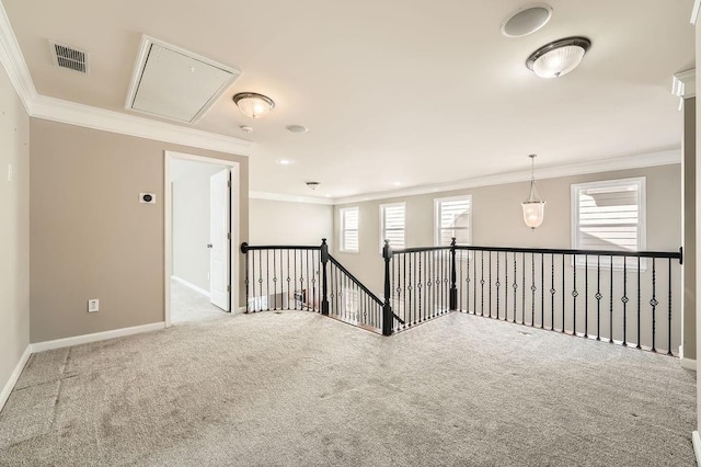 spare room with carpet floors, ornamental molding, visible vents, and attic access