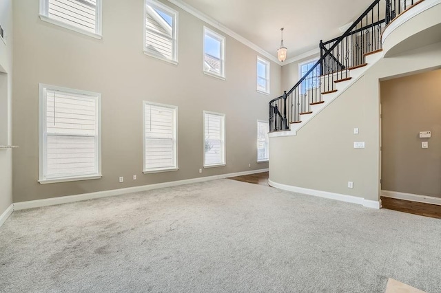 unfurnished living room with carpet floors, a high ceiling, and baseboards