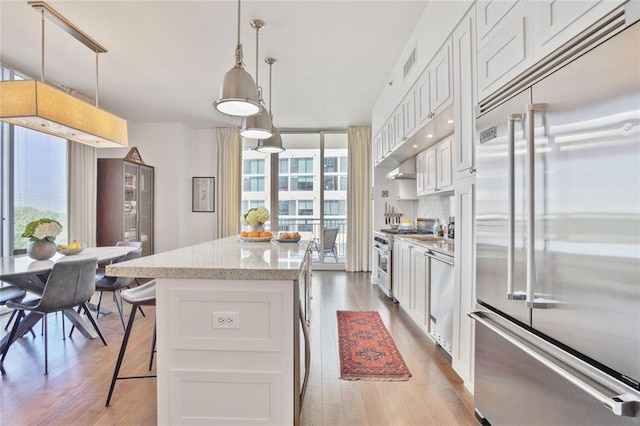 1820 Peachtree St NW Unit 1008, Atlanta, GA 30309 - kitchen with premium appliances, a center island, light wood-style flooring, light stone countertops, and white cabinets
