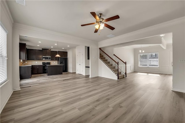 unfurnished living room featuring light wood-style floors, stairs, a ceiling fan, and crown molding