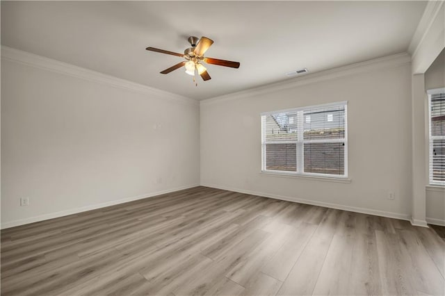 spare room featuring a healthy amount of sunlight, crown molding, visible vents, and wood finished floors