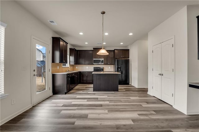 kitchen featuring light countertops, visible vents, backsplash, dark brown cabinetry, and black appliances