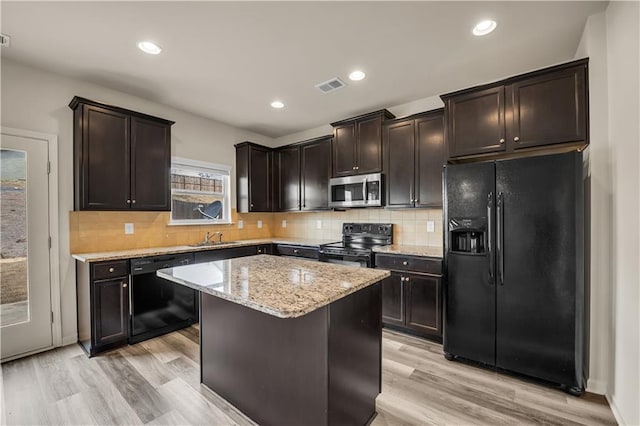 kitchen with light stone counters, visible vents, decorative backsplash, light wood-style floors, and black appliances