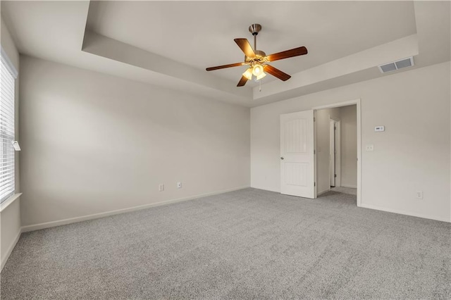 carpeted spare room featuring ceiling fan, baseboards, visible vents, and a raised ceiling