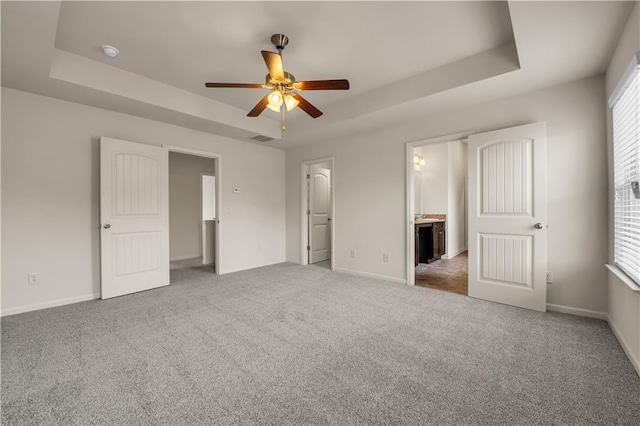 unfurnished bedroom featuring carpet, baseboards, visible vents, and a raised ceiling