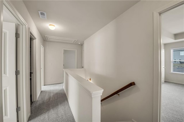 hallway featuring light carpet, baseboards, visible vents, and an upstairs landing