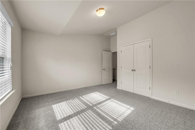 unfurnished bedroom with lofted ceiling, multiple windows, and carpet floors