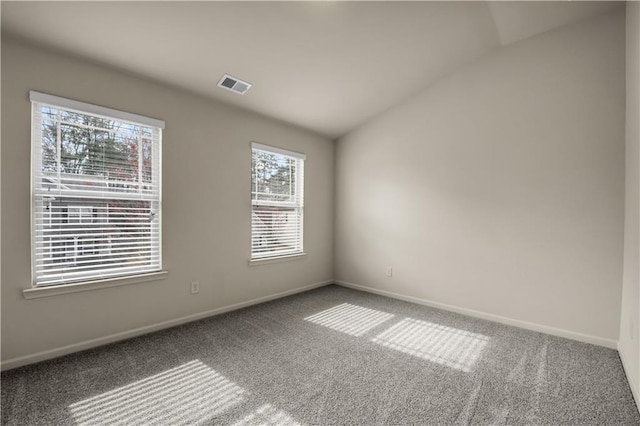 carpeted spare room with baseboards, visible vents, and vaulted ceiling