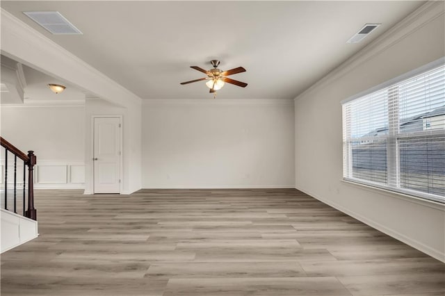 spare room with light wood-type flooring, visible vents, crown molding, and stairway