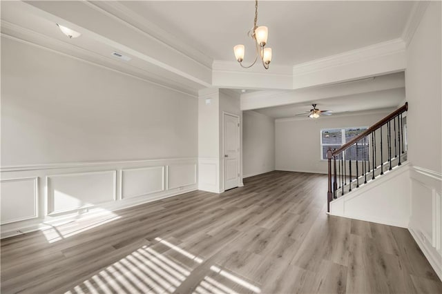 empty room featuring ornamental molding, visible vents, stairway, and light wood finished floors