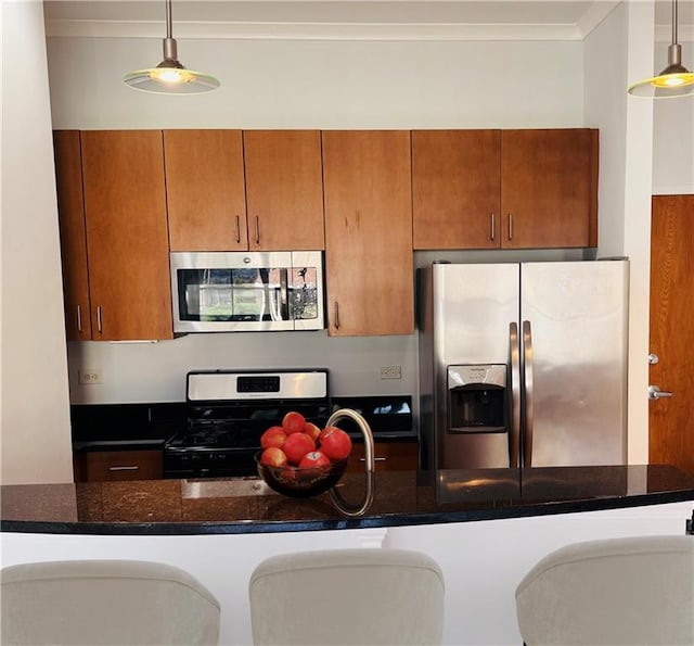 kitchen featuring appliances with stainless steel finishes, brown cabinets, dark stone countertops, hanging light fixtures, and crown molding