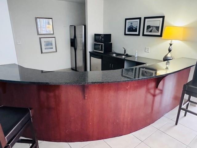 384 Ralph Mcgill Blvd NE Unit 121, Atlanta, GA 30312 - kitchen featuring light tile patterned floors, a breakfast bar, a sink, and appliances with stainless steel finishes