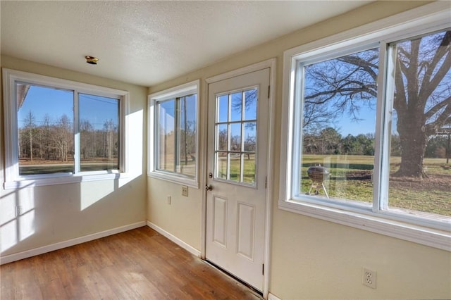 doorway featuring a textured ceiling, baseboards, and wood finished floors