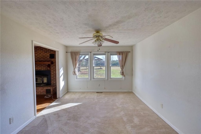 unfurnished living room with light carpet, a wood stove, and baseboards