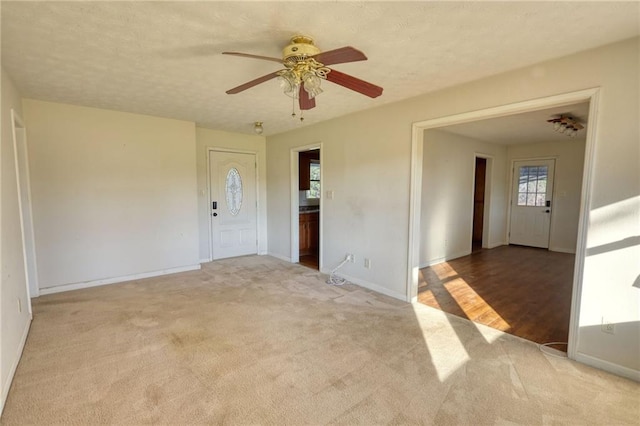 spare room with light carpet, a textured ceiling, and baseboards