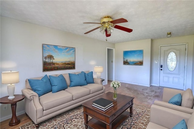 living room with ceiling fan, baseboards, and a textured ceiling