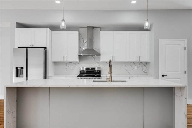 kitchen featuring a kitchen island with sink, a sink, stainless steel appliances, wall chimney range hood, and backsplash