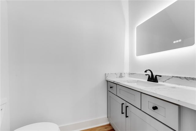 half bathroom with vanity, toilet, and baseboards