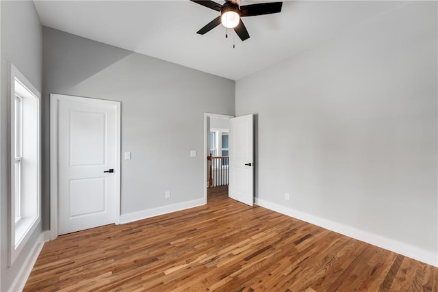 unfurnished bedroom featuring multiple windows, baseboards, ceiling fan, and light wood finished floors