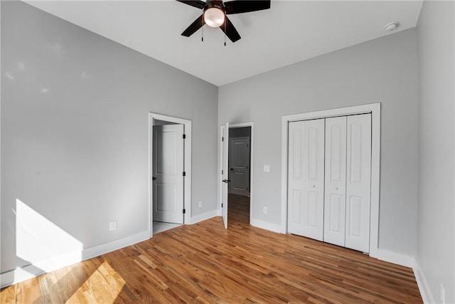 unfurnished bedroom featuring a closet, ceiling fan, baseboards, and wood finished floors