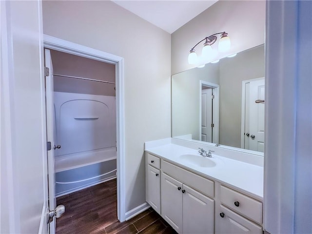 full bathroom with shower / washtub combination, vanity, baseboards, and wood finished floors