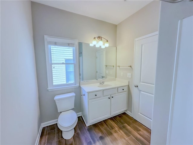 bathroom with vanity, toilet, wood finished floors, and baseboards