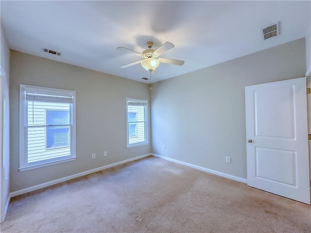 carpeted spare room featuring visible vents, baseboards, and ceiling fan