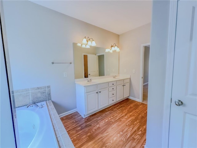 full bath with a sink, a garden tub, wood finished floors, and double vanity