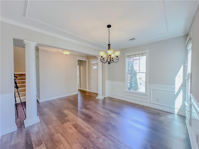 empty room featuring a notable chandelier, stairway, ornate columns, and wood finished floors