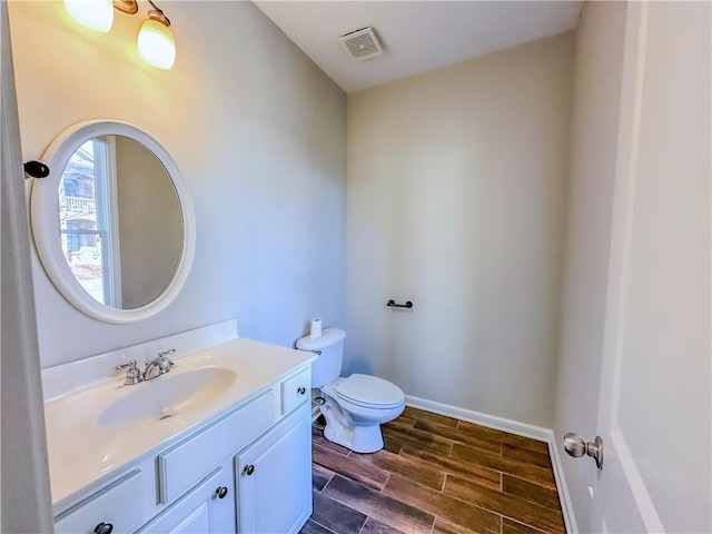 bathroom with wood finish floors, visible vents, toilet, baseboards, and vanity