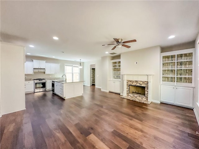 unfurnished living room featuring visible vents, recessed lighting, a fireplace, dark wood-style floors, and a ceiling fan