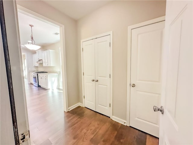 hallway with visible vents, baseboards, and wood finished floors