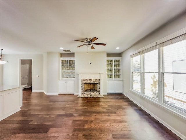 unfurnished living room with visible vents, wood finished floors, a fireplace, and a ceiling fan