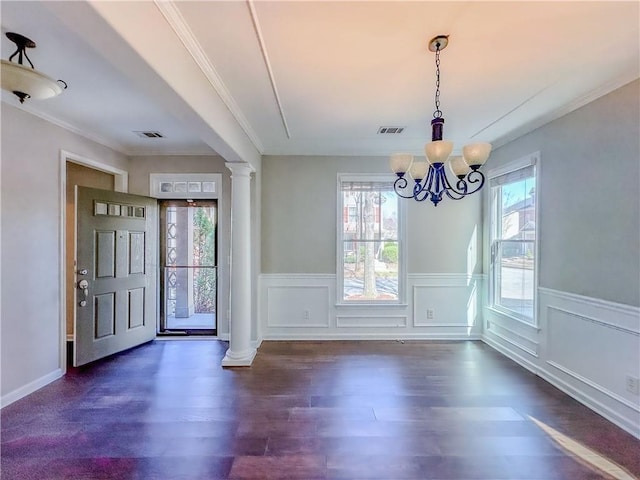 entrance foyer with dark wood-type flooring, decorative columns, visible vents, and a chandelier