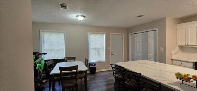 kitchen featuring dark hardwood / wood-style flooring, white cabinets, a textured ceiling, and light stone counters