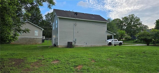 rear view of house with cooling unit and a lawn