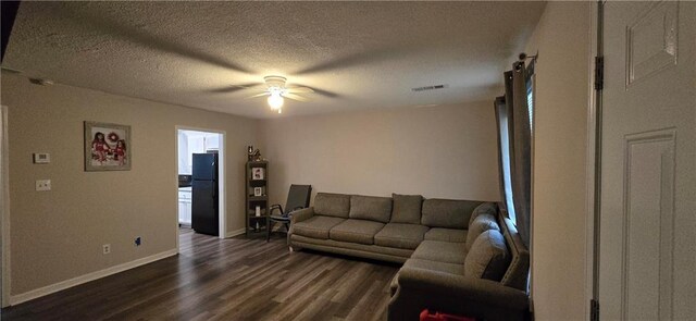 living room featuring dark wood-type flooring, a textured ceiling, and ceiling fan