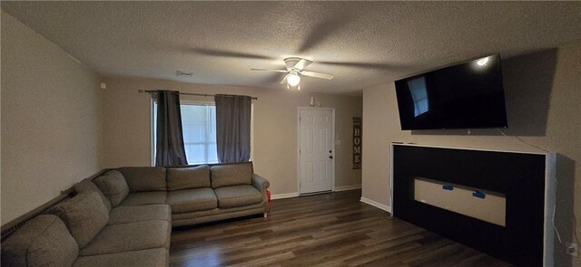 living room featuring dark hardwood / wood-style floors, a textured ceiling, and ceiling fan