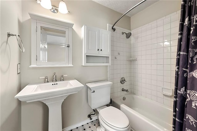 bathroom featuring baseboards, a sink, shower / bath combination with curtain, a textured ceiling, and toilet