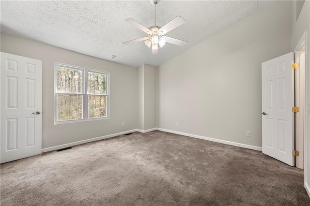 carpeted empty room with visible vents, baseboards, lofted ceiling, a textured ceiling, and a ceiling fan