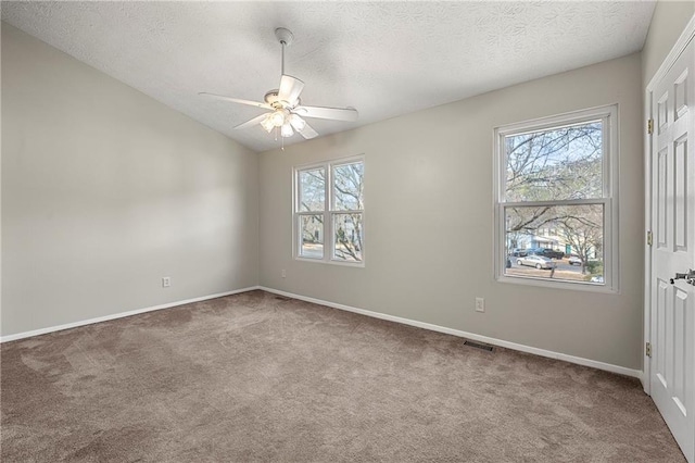 carpeted spare room featuring visible vents, lofted ceiling, a healthy amount of sunlight, and a ceiling fan