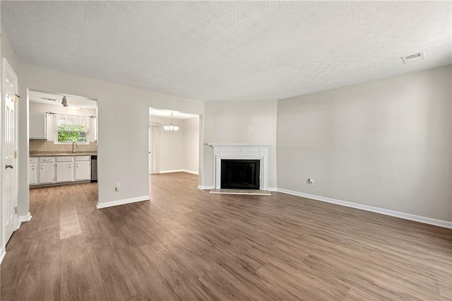 unfurnished living room featuring a sink, visible vents, wood finished floors, and a fireplace