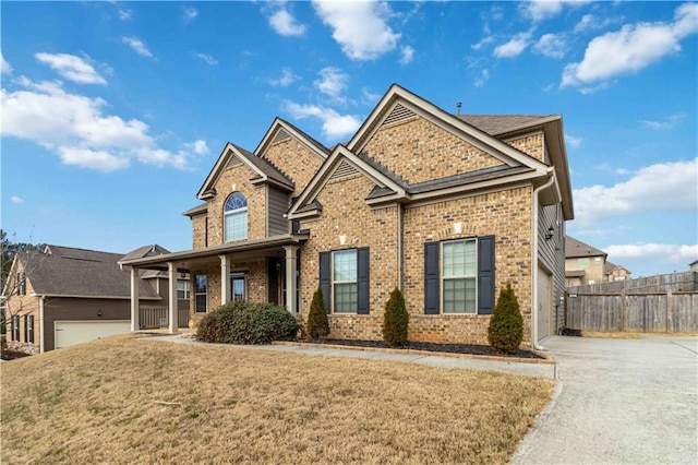 view of front of property with concrete driveway, brick siding, a front yard, and fence