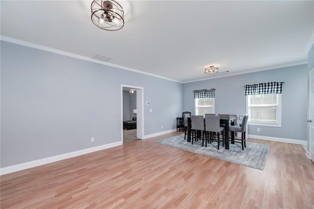 dining space with crown molding, a chandelier, and light hardwood / wood-style flooring